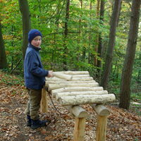 Ein Kind spielt ein Baumstamm-Xylophon
